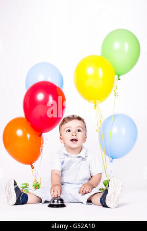 Glückliches Baby Boy mit Haufen Luftballons isoliert auf weiss Stockfoto