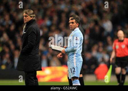 Carlos Tevez (Mitte) von Manchester City wartet auf der Touchline mit manager Roberto Mancini (links), bevor er auf den Platz gewechselt wurde Stockfoto