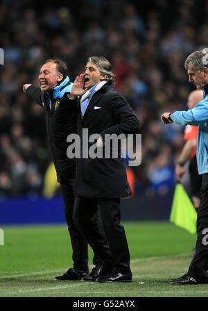 Roberto Mancini (Mitte), Manager von Manchester City, und erster Teamtrainer David Platt (links) ruft als Assistant Manager an der Touchline Brian Kidd (rechts) überprüft seine Uhr Stockfoto