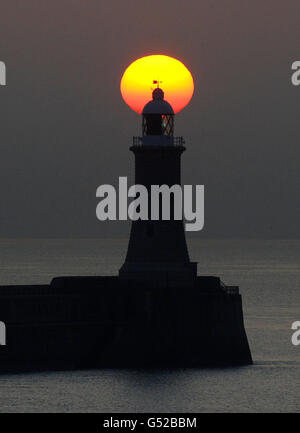 Die Sonne geht über dem Leuchtturm am Tynemouth Pier, Tyne and Wear auf. Stockfoto