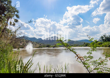 Namibia, Kunene, Kaokoland, Kunene vor einer Bergkette unter einem bewölkten Himmel, Epupafalls, Fluss an der Grenze zu Angola im Kaokoland Stockfoto