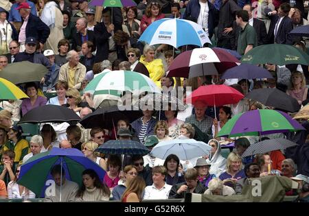 Keine kommerzielle Nutzung : Tennis-Fans legen ihre Regenschirme auf, als Regen auf dem Center Court während des Männer-Singles-Finales zwischen Pete Sampras und Pat Rafter heute, Sonntag, 9. Juli 2000, in Wimbledon fällt. **EDI** PA Foto : Fiona Hanson Stockfoto