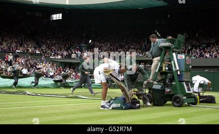 Keine kommerzielle Nutzung : Pat Rafter aus Australien (links) packt seine Taschen, nachdem der Regen während des Männer-Singles-Finales gegen American Pete Sampras in Wimbledon am heutigen Sonntag, 9. Juli 2000, auf dem Center Court zu fallen begann. **EDI** PA Foto : Rebecca Naden Stockfoto