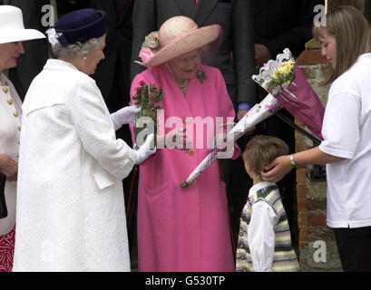 Die Königin, links, und die Königin-Mutter treffen sich auf gute Spieler, während sie die Kirche auf dem Sandringham Estate, Norfolk, mit Cannon George Hall, rechts, verlassen. Stockfoto