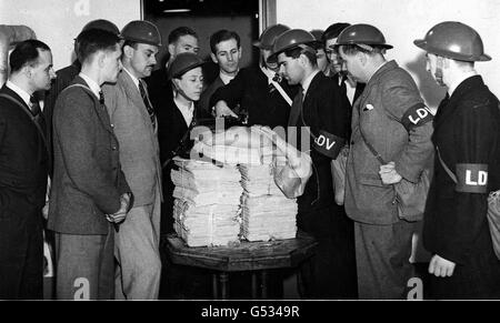 LOKALE FREIWILLIGE DER VERTEIDIGUNG 1940: BBC-Mitarbeiter der LDV (später umbenannt in Home Guard) inspizieren ein Lee Enfield .303 Gewehr. Die Männer tragen ihre Zivilkleidung, außer Helm, Armband und Gasmaskenhalter. Bild Teil der PA Zweiten Weltkrieg Sammlung. Stockfoto