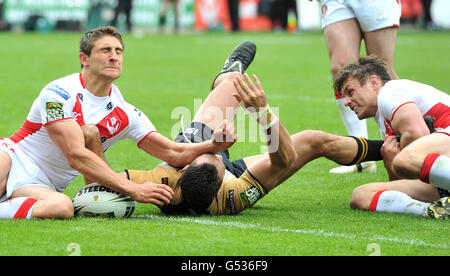 Wigans George Carmontvgeht auf einen Versuch über, als er von St. Helens' Jon Wilkin (rechts) und Tommy Makinson (links) während des Stobart Super League-Spiels im Langtree Park, St. Helens, in Angriff genommen wird. Stockfoto