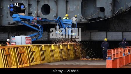 Auf der Govan Shipyard von BAE Systems in Glasgow, Schottland, sind Arbeiter neben einem Rumpfabschnitt der HMS Queen Elizabeth abgebildet. Stockfoto