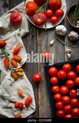 Stillleben mit Tomaten. Frische Erbstück Cherry-Tomaten, Bio-Tomaten, Knoblauch und Thymian auf rustikalen hölzernen Hintergrund Stockfoto