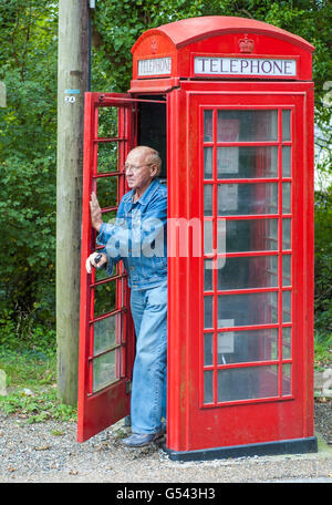 Mann zu Fuß aus einem alten Stil britische rote Telefonzelle in Amberley, West Sussex, Littlehampton, England, UK. Stockfoto