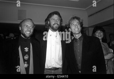 Die Bee Gees, von links nach rechts, die Brüder Maurice, Barry und Robin Gibb bei den Ivor Novello Awards im Londoner Grosvenor House Hotel, nachdem sie aus Amerika für die Zeremonie, die von den Songwritern, Komponisten und Autoren der British Academy veranstaltet wurde, eingeflogen waren. Stockfoto