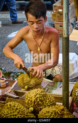 Ein junger Mann bereitet Durian für den Vertrieb in seinem Stall auf Chun Yeung Street in Northpoint, Hong Kong Stockfoto