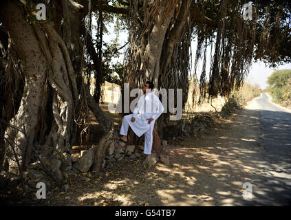 Mann, der von riesigen holzigen Baumstamm mit authentischen nisht zu unterscheidend verbunden Prop Luftwurzeln, seine Identität zu erkunden. Stockfoto