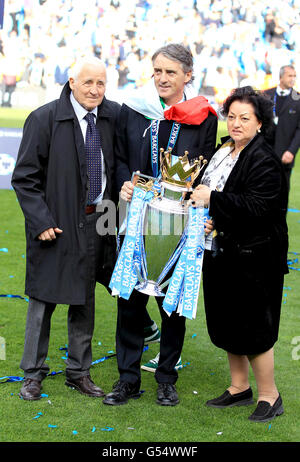 Roberto Mancini, Manager von Manchester City, mit einer italienischen Flagge gehüllt, feiert mit seinem Vater Aldo (links) und seiner Mutter Marianna die Barclays Premier League Trophy Stockfoto