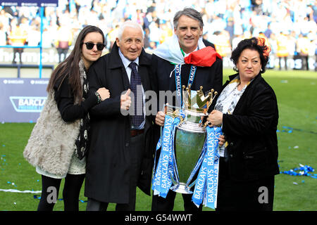 Roberto Mancini, Manager von Manchester City, mit einer italienischen Flagge gehüllt, feiert mit seinem Vater Aldo (2. Links) und seiner Mutter Marianna (rechts) die Barclays Premier League Trophy Stockfoto