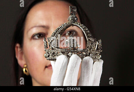 Die Kuratorin der Ausstellung Caroline de Guitaut hält die kleine Diamantkrone von Queen Victoria, die sie anlässlich ihres Diamond Jubilee in der Queen's Gallery im Buckingham Palace im Zentrum von London trug.Sie ist Teil einer Ausstellung königlicher Juwelen, die anlässlich der 60-jährigen Regierungszeit der Queen inszeniert werden. Stockfoto