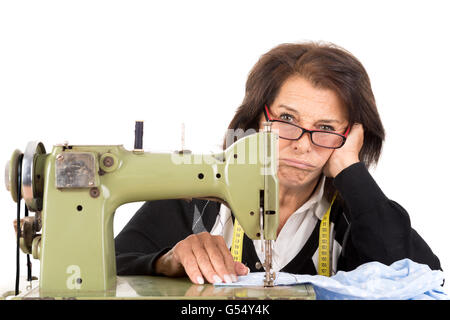Gestresste senior Frau mit Nähmaschine isoliert in weiß Stockfoto