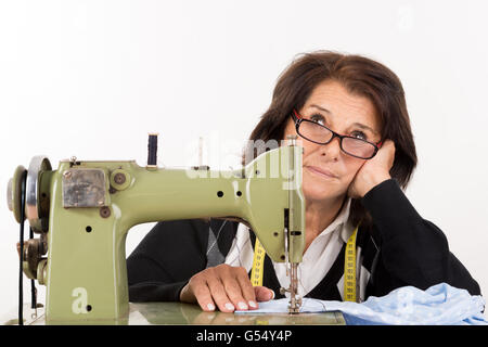 Gestresste senior Frau mit Nähmaschine isoliert in weiß Stockfoto