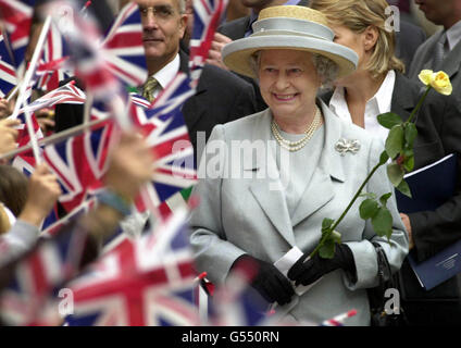 Königin Elisabeth II. Lächelt herzlich, als sie am letzten Tag des Staatsbesuchs in Italien eine gelbe Rose in der Form hält, die ihr Kinder einer britischen Schule auf der Piazza San Fedele in Mailand überreicht haben. Stockfoto