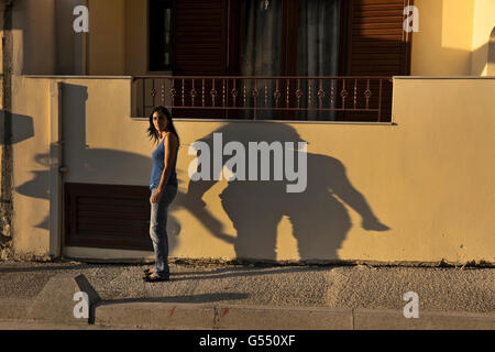 Eine Frau mittleren Alters wirft einen Schatten, während sie durch das Dorf Anogia auf Kreta in Griechenland geht Stockfoto
