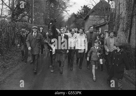 Highland Wedding, Gewinner der gestrigen Grand National Steeplechase, macht durch Fyfield, Hampshire, einen Heldenfortschritt, nachdem er nach seinem Triumph bei Aintree in den Stall von Trainer Toby Balding (mit Brille rechts) mit Jockey Eddie Harty, der Hand auf Pferd hat, zurückgekehrt ist. Stockfoto