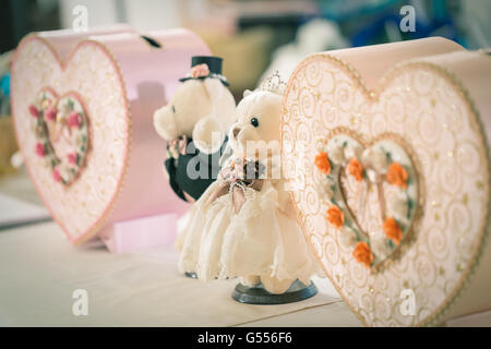 Enge Fokussierung auf Braut tragen Puppe neben mit Bräutigam Bär Puppe und rosa Papier-Boxen in Herzform für Hochzeitsnacht dekoriert Stockfoto