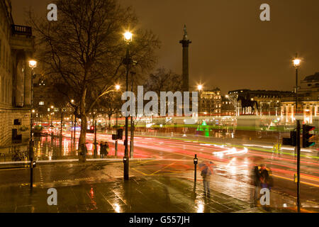 London, England, Trafalgar Square nachts im Regen mit Doppeldecker-Busse, Menschen mit Regenschirmen Stockfoto