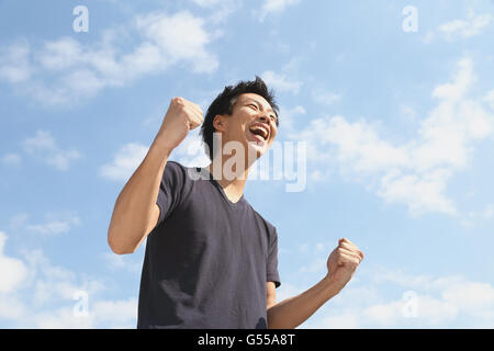 Junge Japaner jubeln gegen blauen Himmel Stockfoto