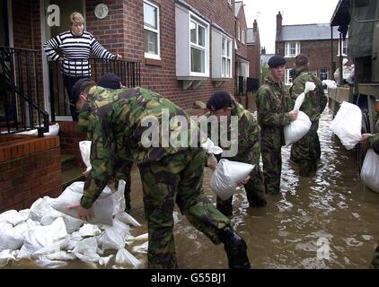 Ein Bewohner beobachtet, wie die Armee die Verteidigung in der River Street in der Gegend von Clementhorpe in York, North Yorkshire, stärkt. Die Gemeinden in Yorkshire sind auf dem neuesten Stand, da sie auf neue Hochwasserspitzen warten, die ihren Häusern weitere Verwüstungen bringen könnten. *...Rettungsdienste haben die Städte Barlby und Selby als die wichtigsten Krisenherde ausfindig gemacht. Stockfoto