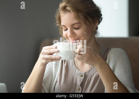 Brustbild des jungen schönen weiblichen sitzen im Café mit Tee oder Cappuccino. Frau, heißes Getränk genießen Stockfoto