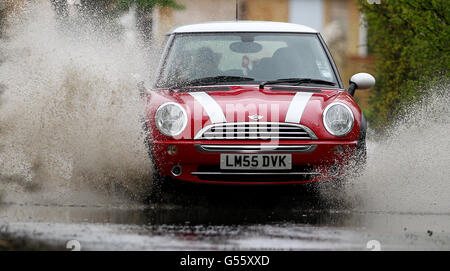 Ein Auto fährt in Ashford, Kent, nach heftigen Regenfällen über Nacht durch eine überflutete Straße. Stockfoto