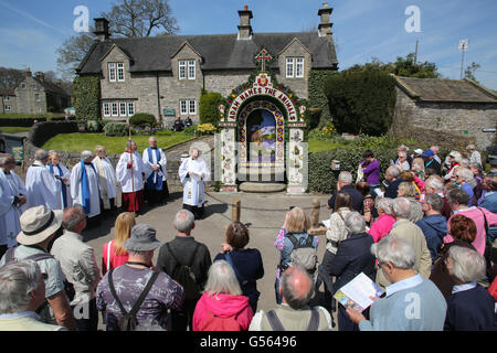 Eine Masse beobachtet, wie Mitglieder der lokalen Kirche eine von sechs Bunt gekleidet Brunnen segnen in der derbyshire Dorf tissington. Stockfoto