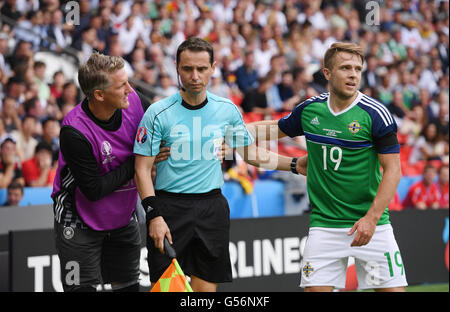 Paris, Frankreich. 21. Juni 2016. Bastian Schweinsteiger Deutschlands und Northern Ireland Jamie Ward (r) helfen Assistent Schiedsrichter Frederic Cano aus Frankreich, nachdem er von einer Kugel in den Magen während der UEFA Euro 2016 Gruppe C-Fußballspiel zwischen Nordirland und Deutschland am Stadion Parc des Princes in Paris, Frankreich, 21. Juni 2016 getroffen wurde. Foto: Arne Dedert/Dpa/Alamy Live-Nachrichten Stockfoto