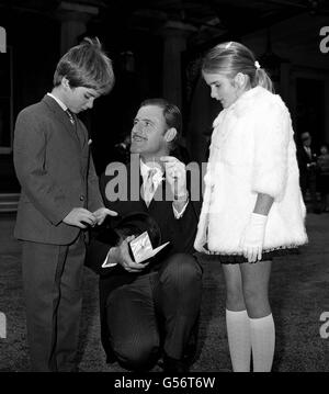 GRAHAM HILL 1968: Rennfahrer Graham Hill zeigt seine Kinder Damon (8), links, und Brigitte (9), die OBE, die er von der Queen Mother bei seiner Investitur im Buckingham Palace, London, erhielt. Die Königin Mutter gratulierte ihm zu seiner zweiten Weltmeisterschaft und fragte nach seinem Sieg im Großen Preis von Mexiko. Stockfoto