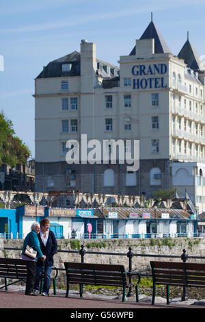 Ein älteres weiblichen Ehepaar mit Blick auf den Strand von der Küstenpromenade von Llandudno in Nordwales mit dem Grand Hotel in hinten an einem Sommertag Stockfoto