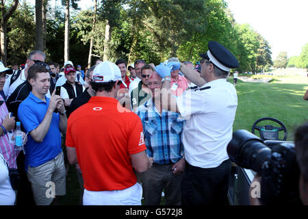 Der nordirische Rory McIlroy spricht mit dem Zuschauer John Clark, nachdem ihn sein Ball am zweiten Tag der BMW PGA Championship im Wentworth Golf Club, Surrey, getroffen hatte. Stockfoto