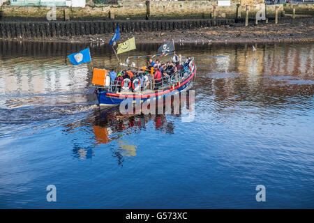 Alten Whitby Rettungsboot nehmen Touristen mit einem Segelboot um Whitby Hafen im Sommer mit vielen Menschen an Bord. Stockfoto