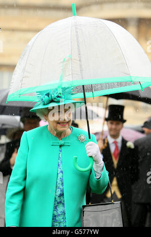 Die britische Königin Elizabeth II. Schützt sich vor dem Regen unter einem Regenschirm, während sie eine Gartenparty im Buckingham Palace im Zentrum von London veranstaltet. Stockfoto