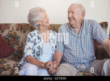 Älteres Paar zusammen Hand in Hand auf dem Sofa sitzen. glücklich, älteres Paar auf der Suche entspannt und zufrieden zusammen. Stockfoto