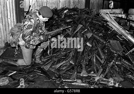 DER FALKLANDKRIEG 1982: Ein Offizier der Royal Marines untersucht ein antiquiertes Maschinengewehr aus einem Stapel automatischer Waffen, die von argentinischen Truppen bei der Goose Green Surrender niedergelegt wurden. Goose Green wurde von Männern des Fallschirmregiments gefangen genommen. *25/03/02 ein Offizier der Royal Marines untersucht ein antiquiertes Maschinengewehr aus einem Stapel von automatischen Waffen, die von argentinischen Truppen bei der Goose Green Surrender im Falkland-Krieg niedergelegt wurden.der 20. Jahrestag der Invasion der Falkland durch argentinische Truppen wird am 2. April 2002 stattfinden. Stockfoto