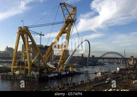 Der weltweit größte Schwebekran Asian Hercules II, bewegt die 850-Tonnen Gateshead Millennium Bridge den Fluss Tyne hinauf, in seine dauerhafte Position. Die 22 Millionen Brücke wird den Fluss Tyne überspannen, um eine Fußgänger- und Fahrradverbindung zu schaffen. * zwischen den Gateshead Quays und dem benachbarten Newcastle's Quayside. Das Design der Struktur ermöglicht es, sich zu drehen, damit Boote unter und die Bewegung der Brücke wurde mit dem Blinzeln eines Auges verglichen. Stockfoto