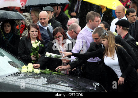 Freunde und Familie schließen sich den Trauernden an, um Blumen auf den Leichenwagen zu legen, der den Sarg des privaten Gregg Thomas Stone vom 3. Bataillon, des Yorkshire Regiments trägt, wie er und CPL Michael John Thacker, vom 1. Batalion, dem Royal Welsh (die Royal Welsh Fusiliers, passieren den Memorial Garden in Carterton, In der Nähe von RAF Brize Norton, Oxfordshire. Stockfoto