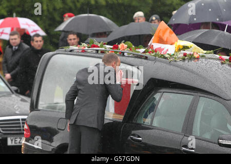 Freunde und Familie schließen sich Trauernden an, um Blumen auf den Leichenwagen zu legen, der den Sarg von KPL Michael John Thacker, vom 1. Batalion, dem Royal Welsh (die Royal Welsh Fusiliers wie er und der Privatmann Gregg Thomas Stone vom 3. Bataillon, dem Yorkshire Regiment, am Memorial Garden in Carterton vorbeiführt, In der Nähe von RAF Brize Norton, Oxfordshire. Stockfoto