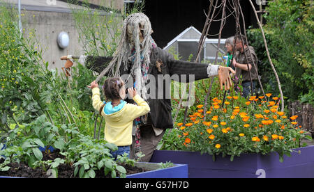 Ein junges Mädchen schaut sich eine Vogelscheuche im Dachgarten auf der Queen Elizabeth Hall in London genauer an, einer von 209 Gärten, die am Open Garden Squares Weekend teilnehmen, das in ganz London stattfindet. Stockfoto