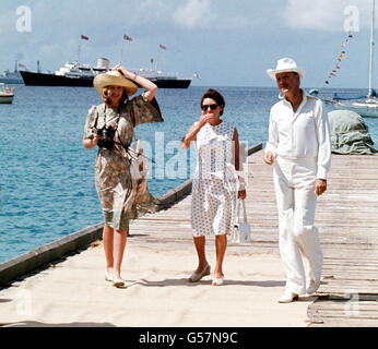 Prinzessin Margaret, Mitte, und ihre Freunde Lady Ann Tennant und Colin Tennant warten auf dem Anlegesteg auf der karibischen Insel Mustique, um Königin Elizabeth II. Zu begrüßen Die Royal Yacht Britannia ist im Hintergrund zu sehen. Stockfoto