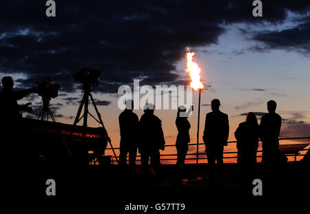 Die Menschen betrachten das Diamond Jubilee Beacon im Edinburgh Castle neben Mons Meg Cannon als die Sonnenuntergänge, nachdem es von Generalmajor Nick Eeles Governer von Edinburgh Castle und General Officer bei der Kommandierung Schottlands beleuchtet wurde. Stockfoto