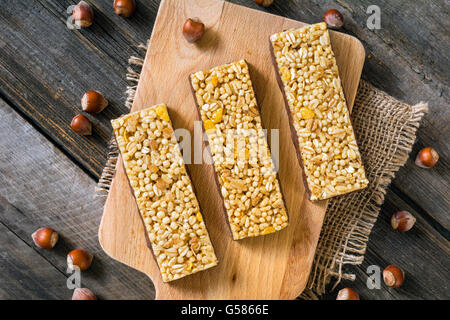 Hausgemachte Müsliriegel mit getrockneten Früchten und Nüssen auf Holzbrett, Tisch-Draufsicht Stockfoto