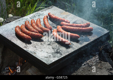 Braten Würstchen auf den heißen Stein in der Natur Stockfoto