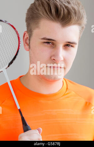 Porträt von einem Teenager. Er hält einen Badminton-Schläger und stehen vor einem einfarbigen Hintergrund Stockfoto