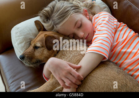 Junges Mädchen streicheln ihren Hund auf dem Sofa zu Hause. Stockfoto