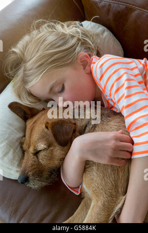 Junges Mädchen streicheln ihren Hund auf dem Sofa zu Hause. Stockfoto